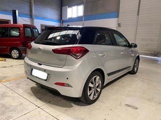 Un coche plateado está aparcado en un garaje al lado de una furgoneta roja.