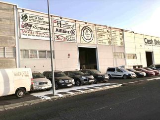 Una fila de coches están aparcados delante de un edificio.