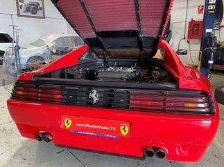 Un Ferrari rojo con la capota levantada está aparcado en un garaje.