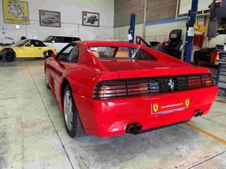 Un Ferrari F355 rojo está aparcado en un garaje.