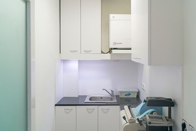 Una cocina con gabinetes blancos, un fregadero y una impresora.