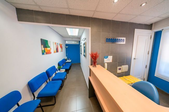 Una sala de espera con sillas azules y un mostrador.