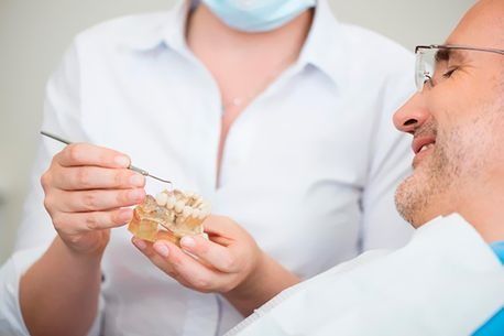 Un dentista sostiene un modelo de los dientes de un hombre.
