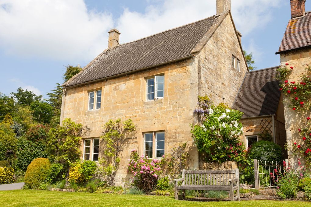 Maison en pierre avec un banc en bois et des fleurs