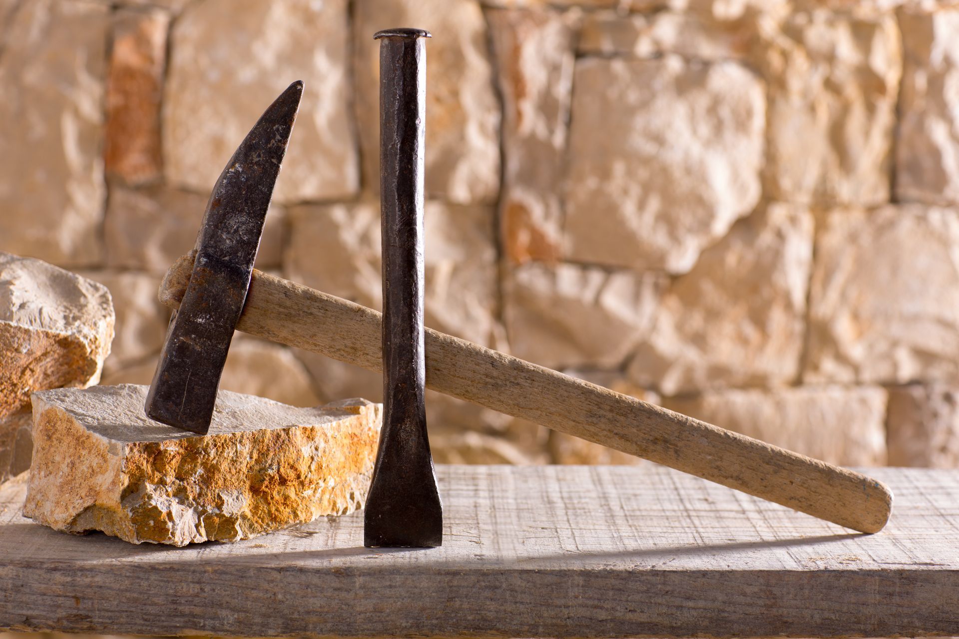 Marteau et burin à côté d'un bloc de pierre