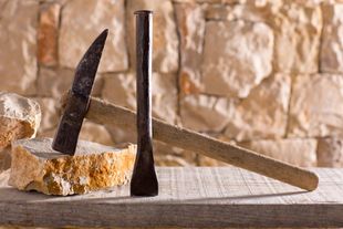 Marteau et burin à côté d'un bloc de pierre