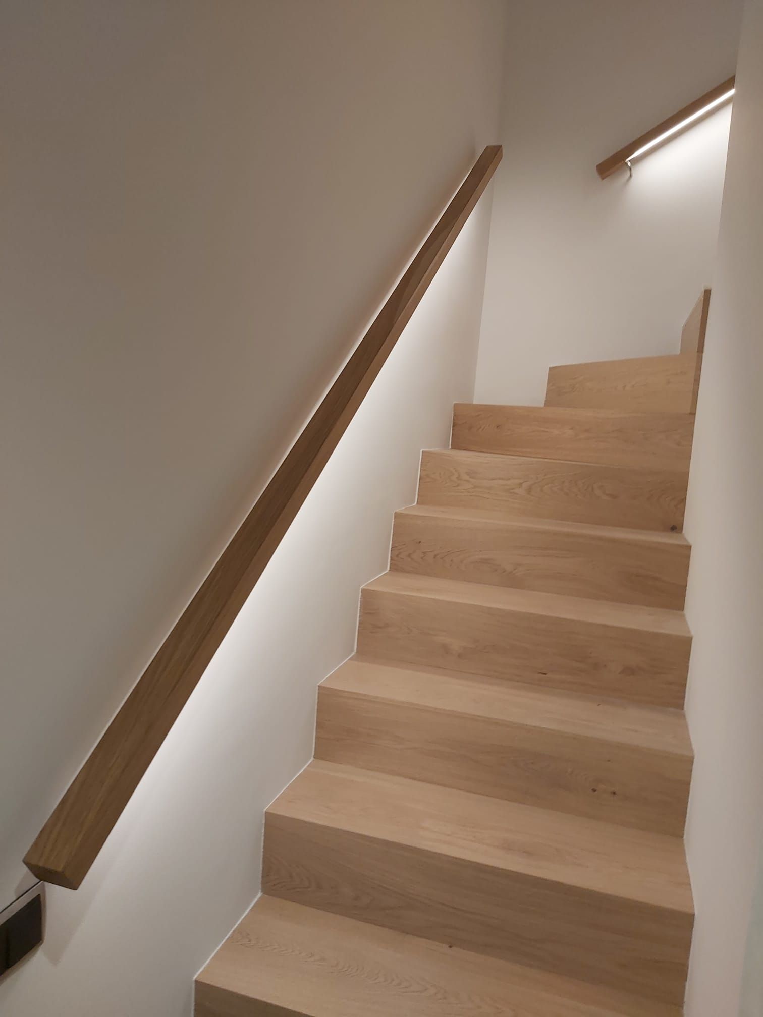 Fachada de edificio de apartamentos de color rojo y crema con múltiples ventanas, vista en ángulo contra un cielo azul.