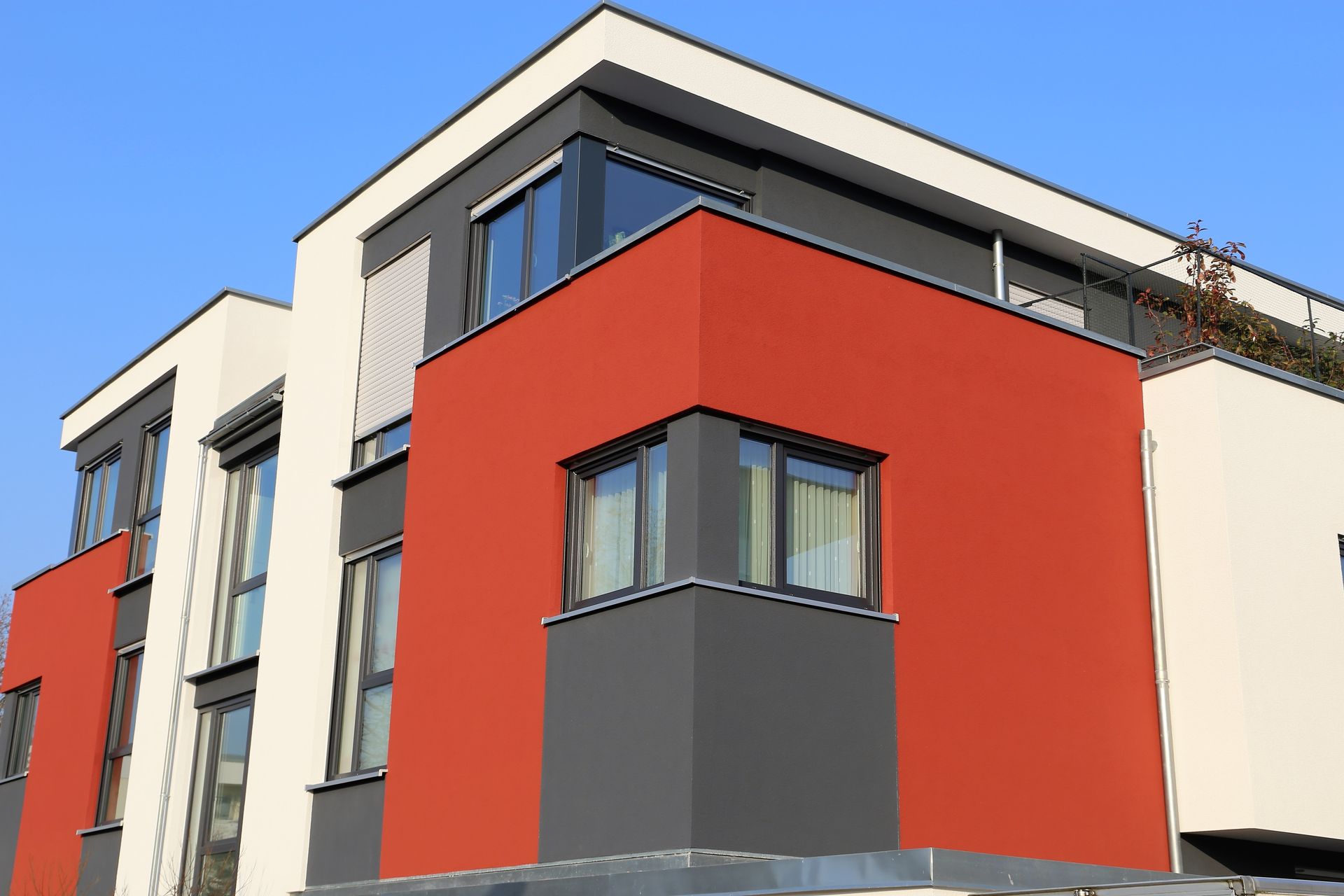 Techador colocando tejas rojas en un techo nuevo. Cielo azul.