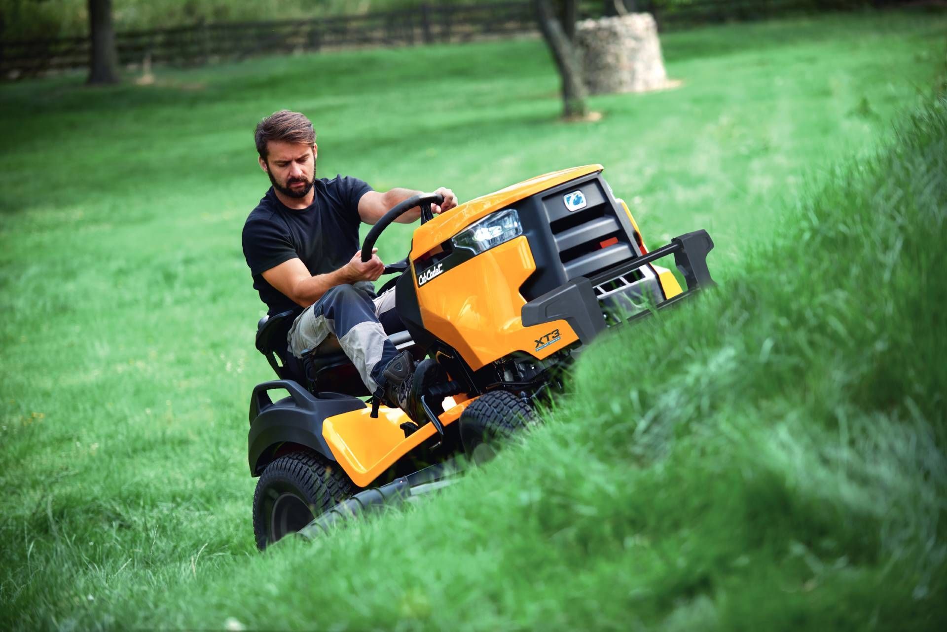 Ein Mann fährt auf einem gelb-schwarzen Traktor und mäht den Rasen