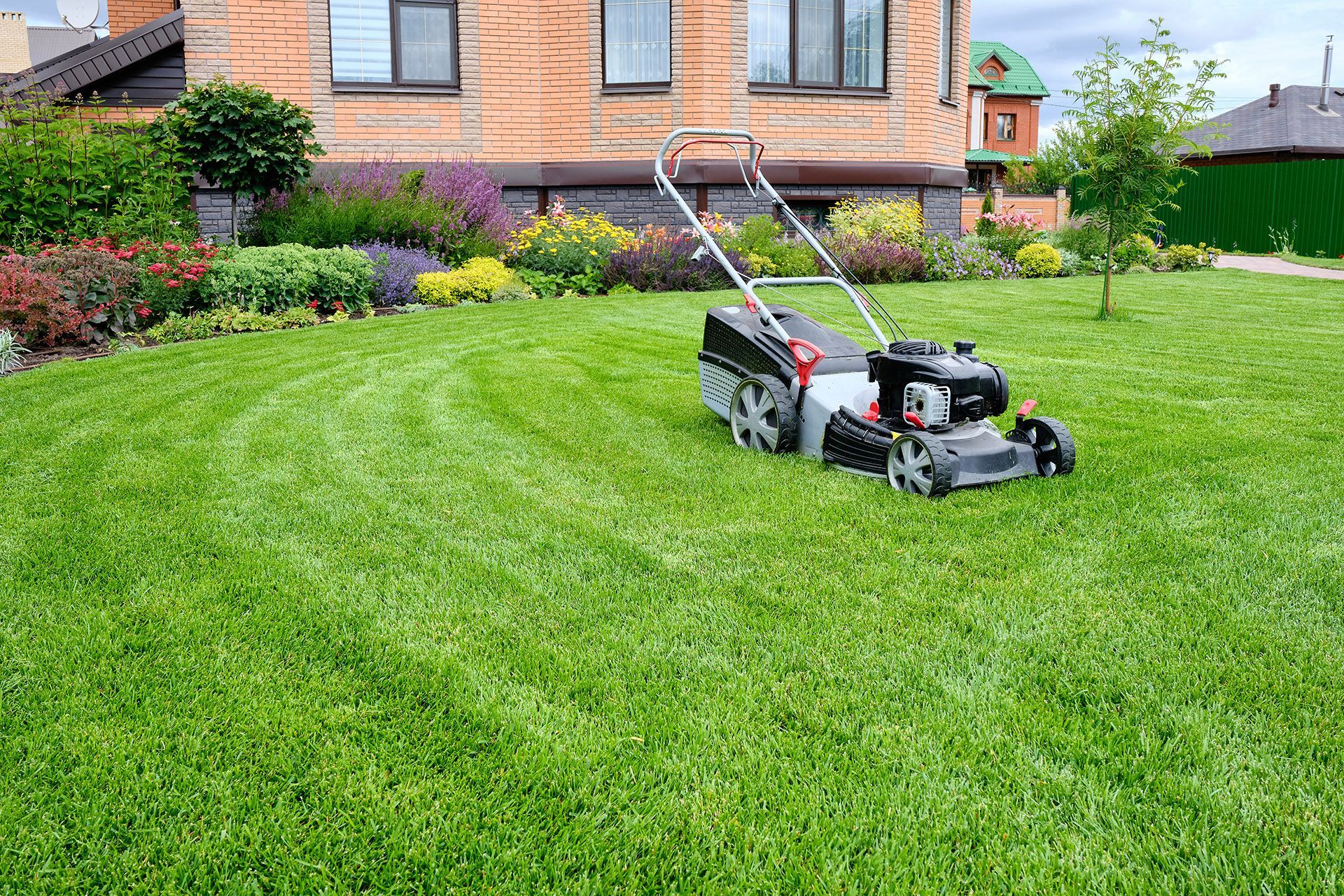 Garten mit Rasenfläche, darauf ein Rasenmäher