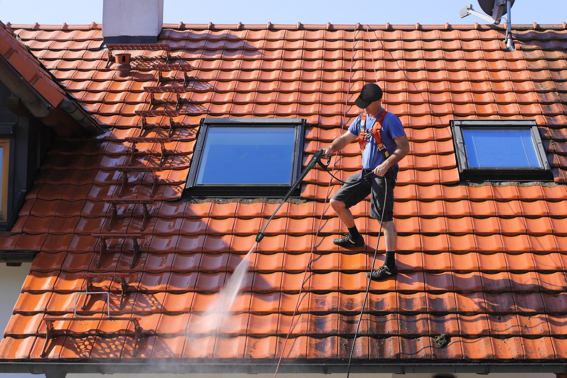 Un homme nettoie une toiture en tuiles