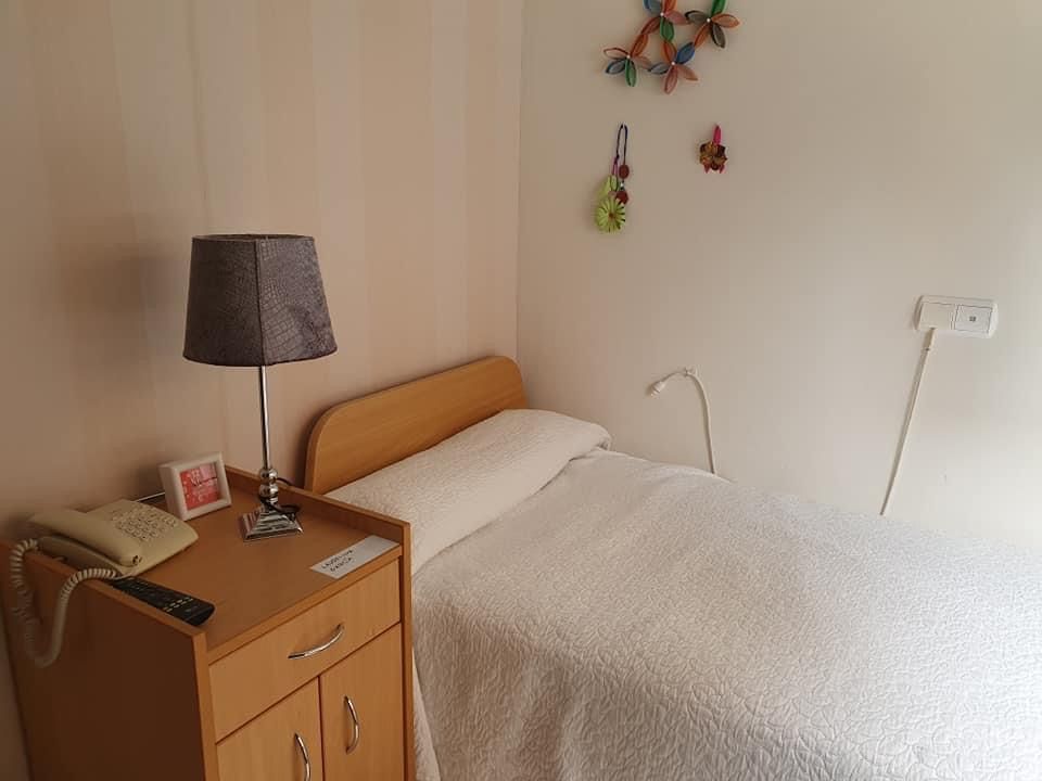 Un dormitorio con cama, mesita de noche, lámpara y teléfono.