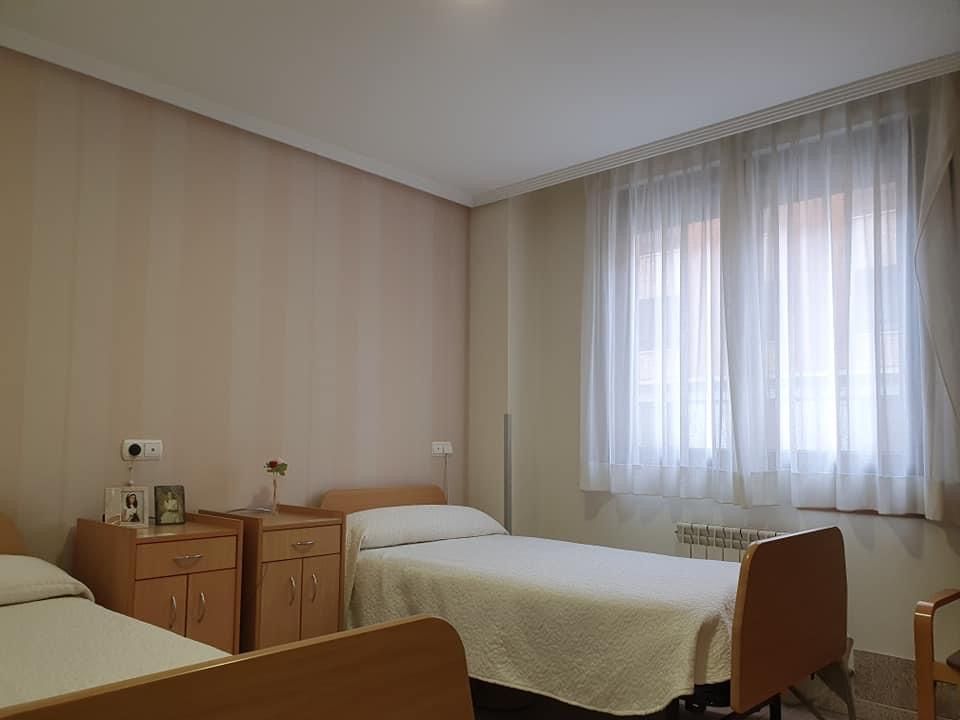 Un dormitorio con dos camas y una ventana con cortinas blancas.