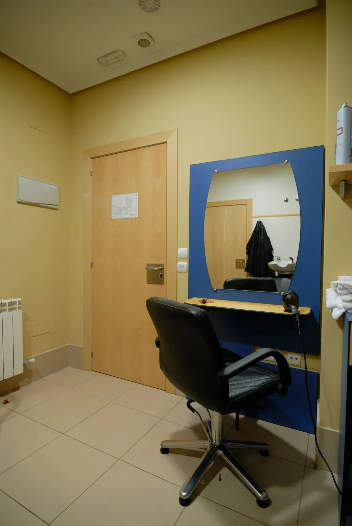 Una habitación con una silla y un espejo en la pared.