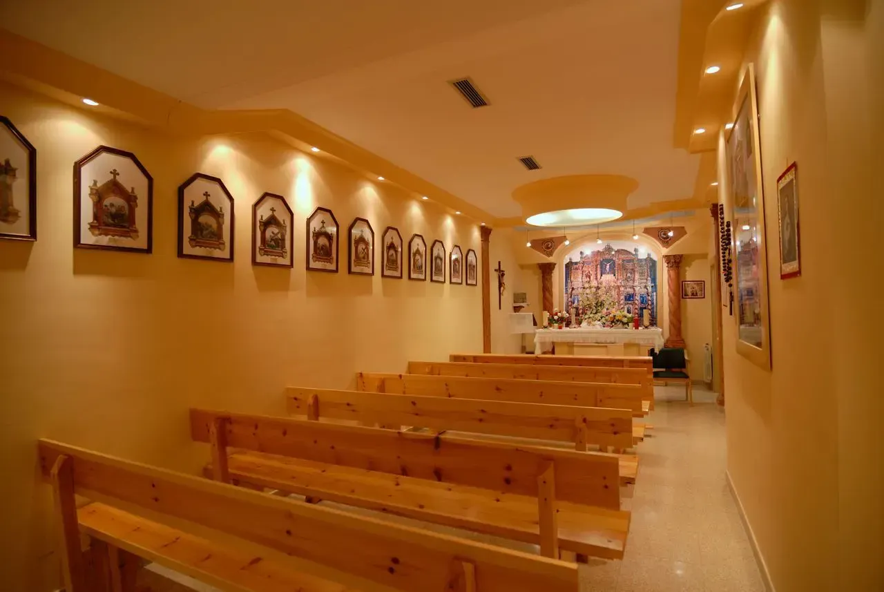 Una iglesia con bancos de madera y cuadros en la pared.