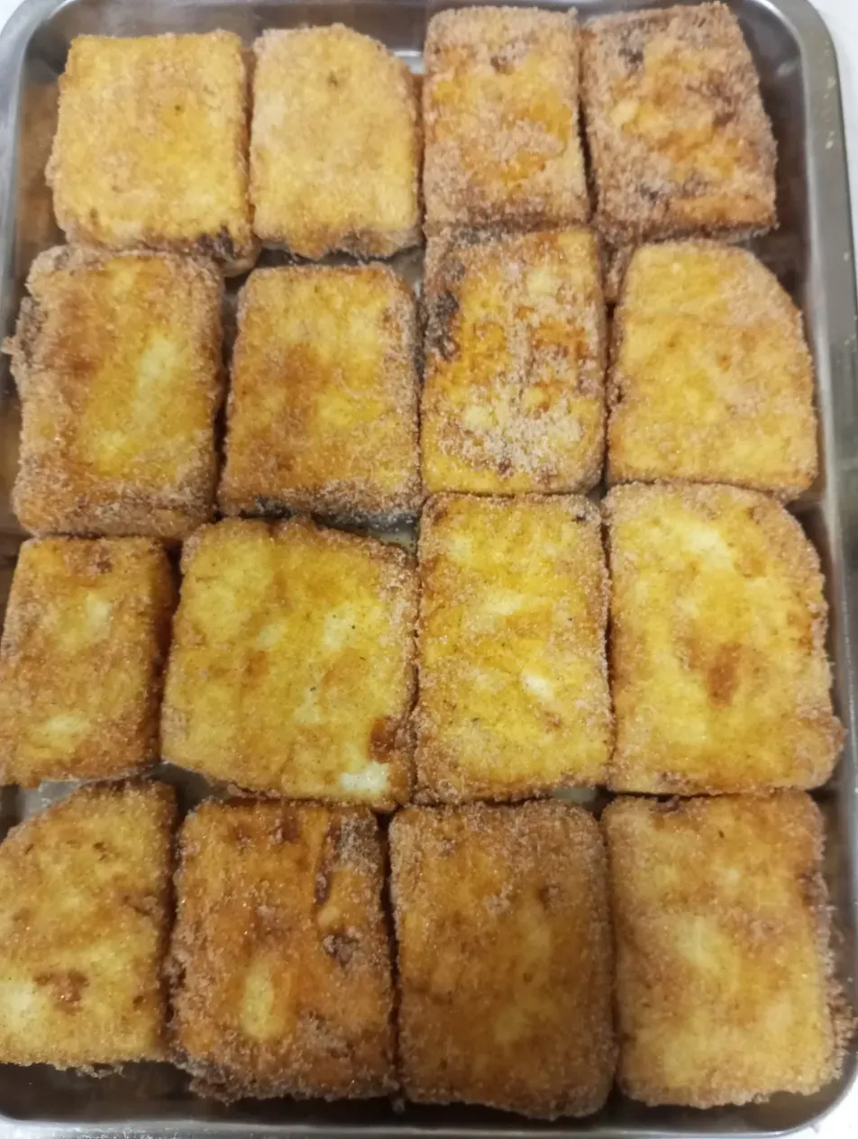 Bandeja de bocadillos cuadrados empanizados de color marrón dorado dispuestos en una cuadrícula de 3x4