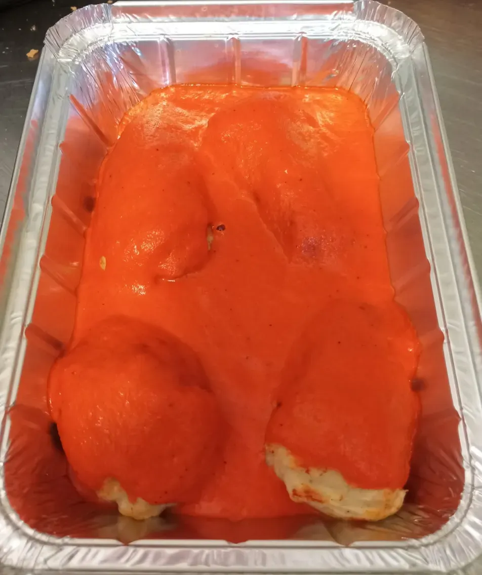 Bandeja de papel de aluminio con salchichas o perritos calientes de color rojo brillante en panecillos, vista desde arriba.