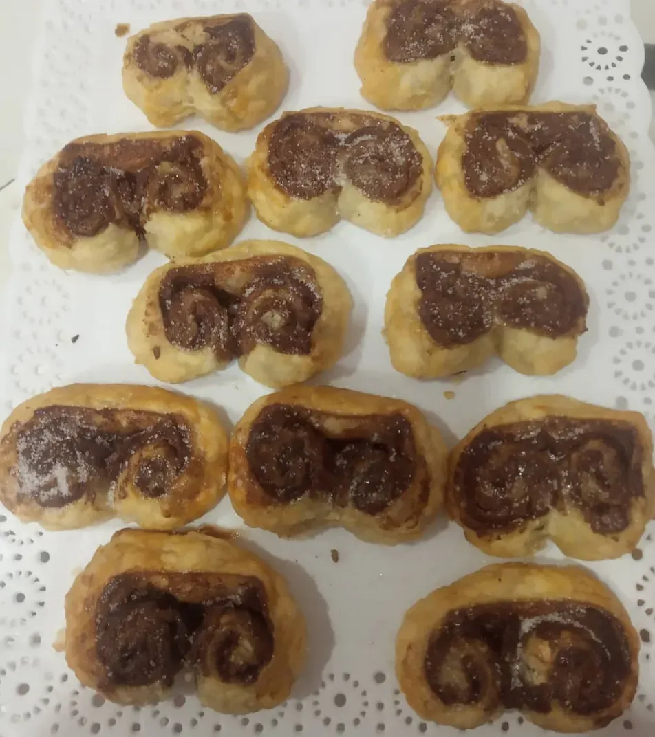 Surtido de pasteles rellenos de chocolate dispuestos en una bandeja forrada con un tapete blanco.