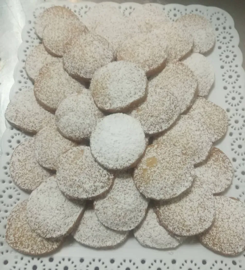 Plato de galletas redondas espolvoreadas con azúcar glas, dispuestas en capas.