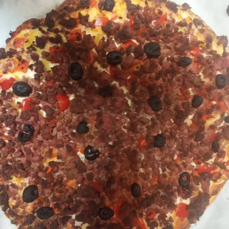 Vista desde arriba de una pizza cubierta con frutos rojos: arándanos, cerezas y fruta roja en cubos.