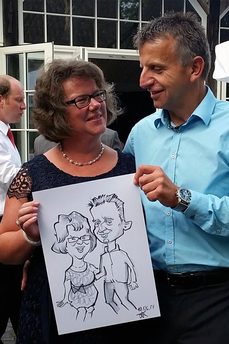 ein Mann und eine Frau stehen nebeneinander und halten eine Karikatur eines Mannes und einer Frau .