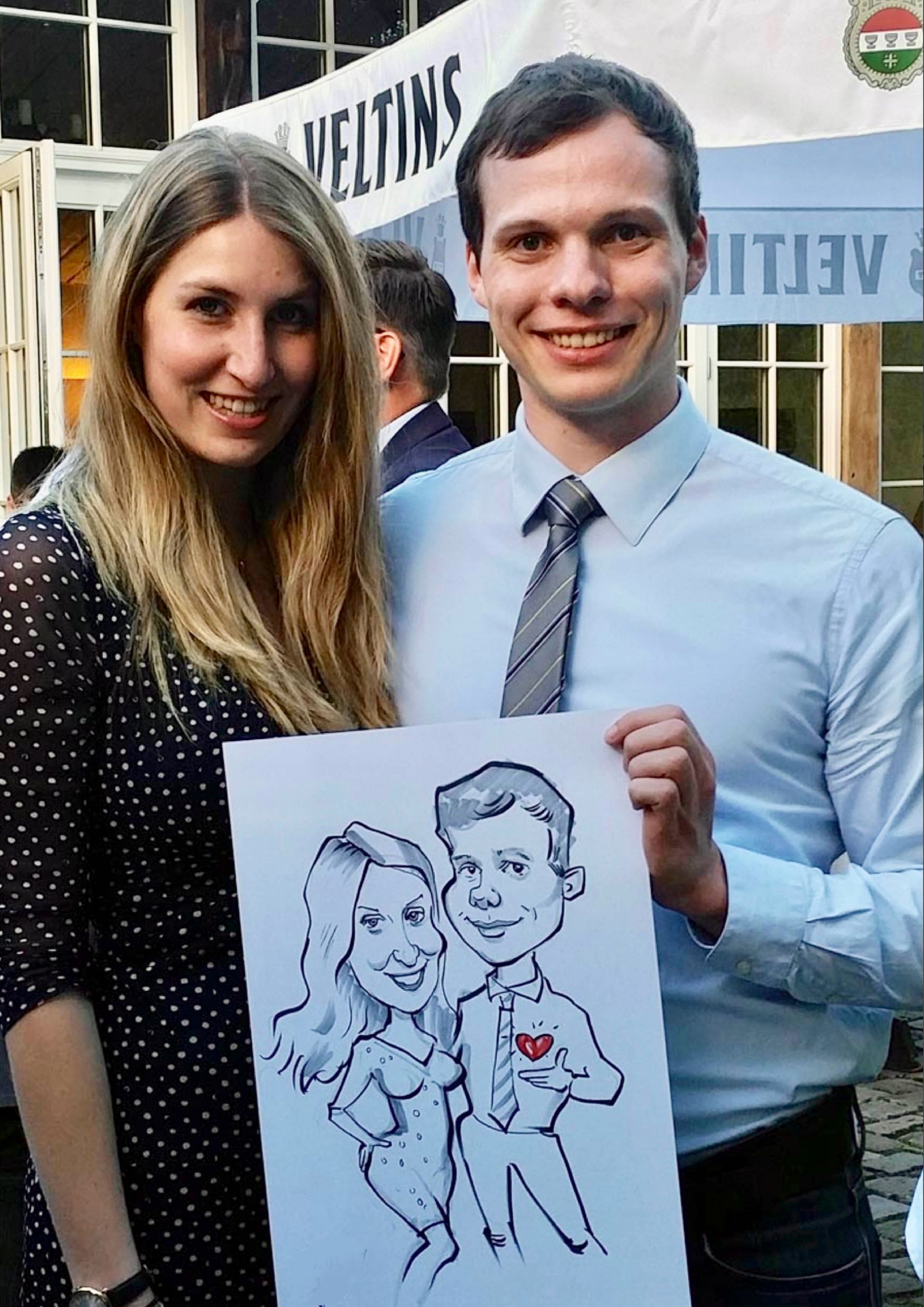 ein Mann und eine Frau stehen nebeneinander und halten eine Karikatur eines Mannes und einer Frau .