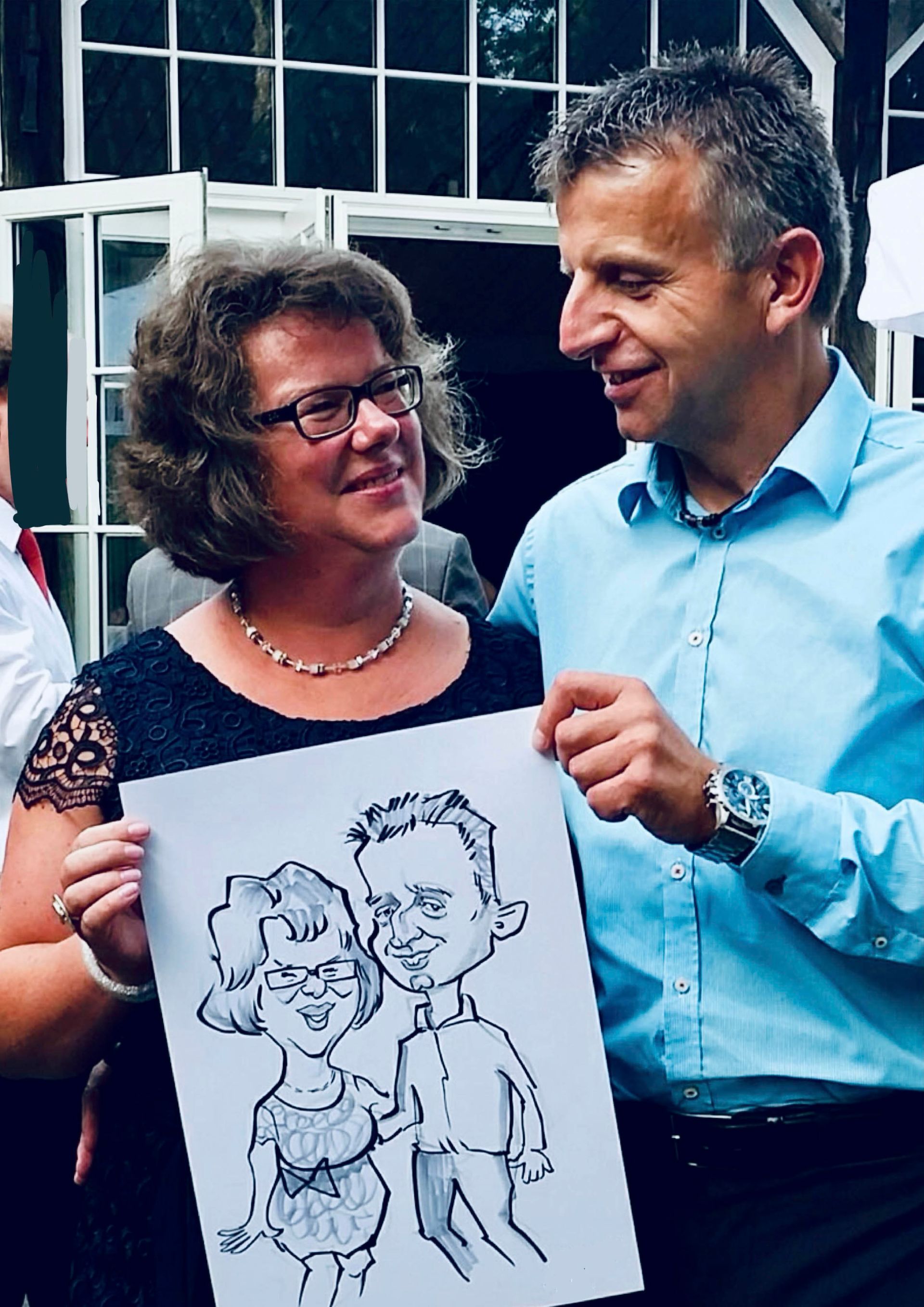 ein Mann und eine Frau stehen nebeneinander und halten eine Karikatur eines Mannes und einer Frau .