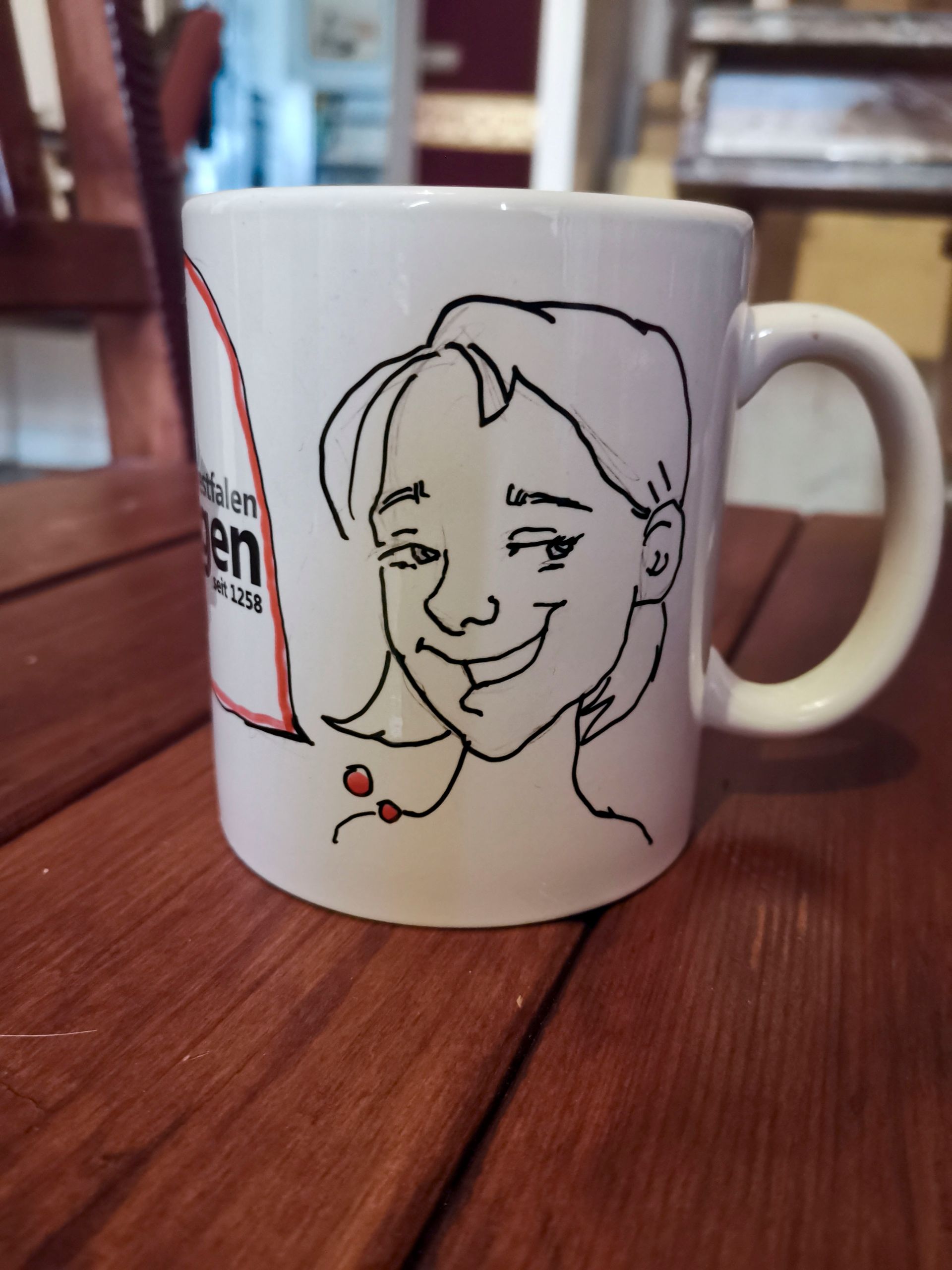 eine weiße Tasse mit einem Bild einer Frau darauf steht auf einem Holztisch