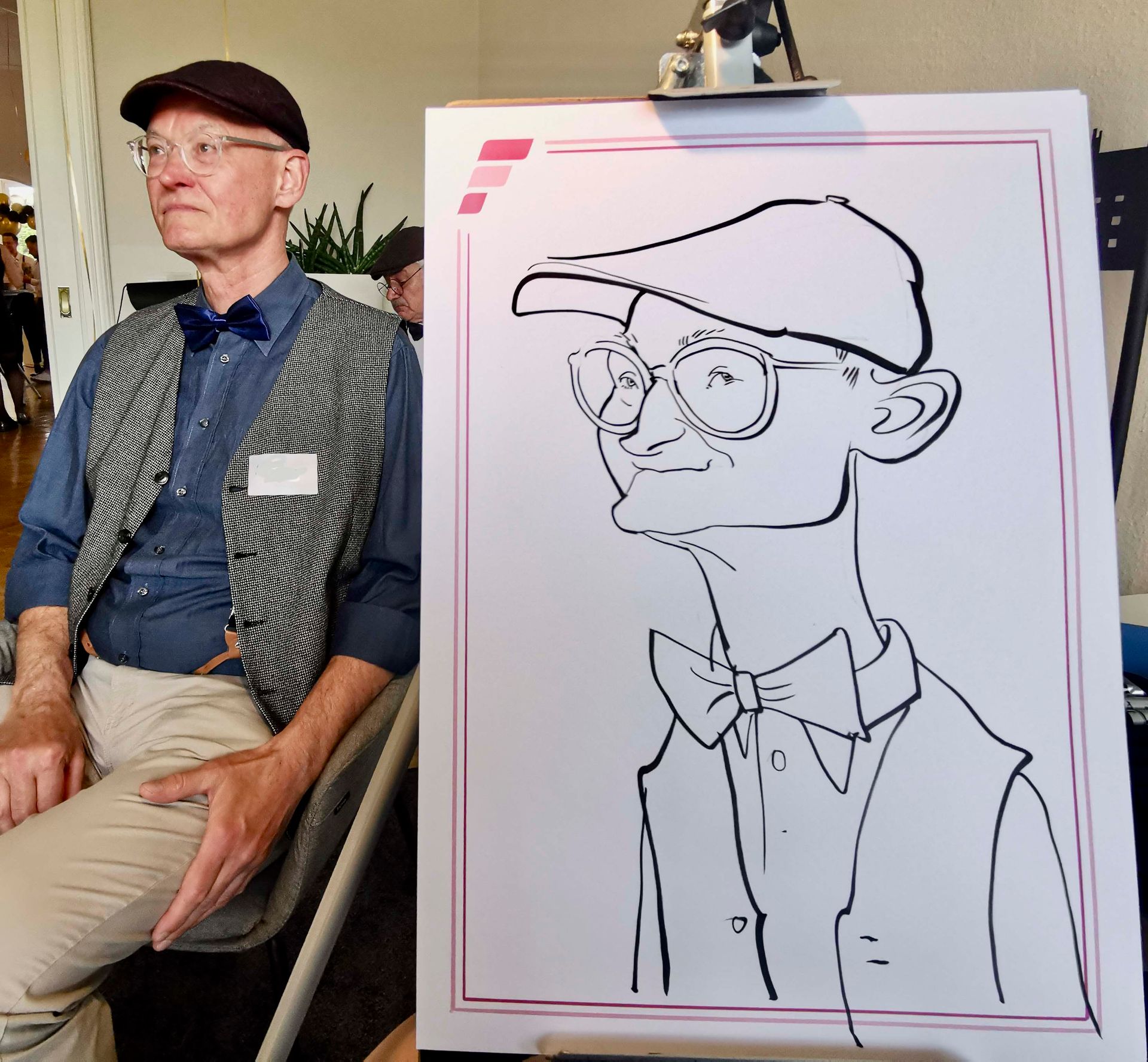 ein Mann sitzt neben einem Schwarz-Weiß-Zeichnung eines Mannes mit Hut und Fliege