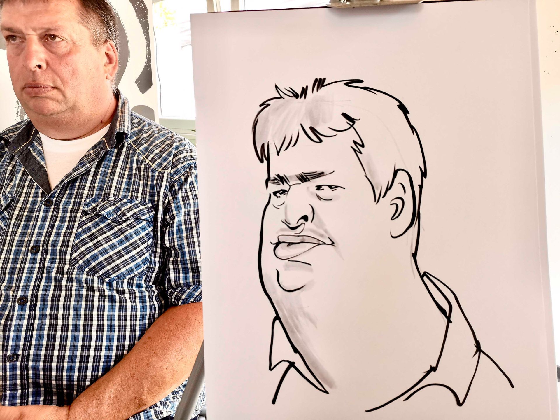 ein Mann in einem karierten Hemd steht neben einem Schwarz-Weiß-Zeichnung eines Mannes .