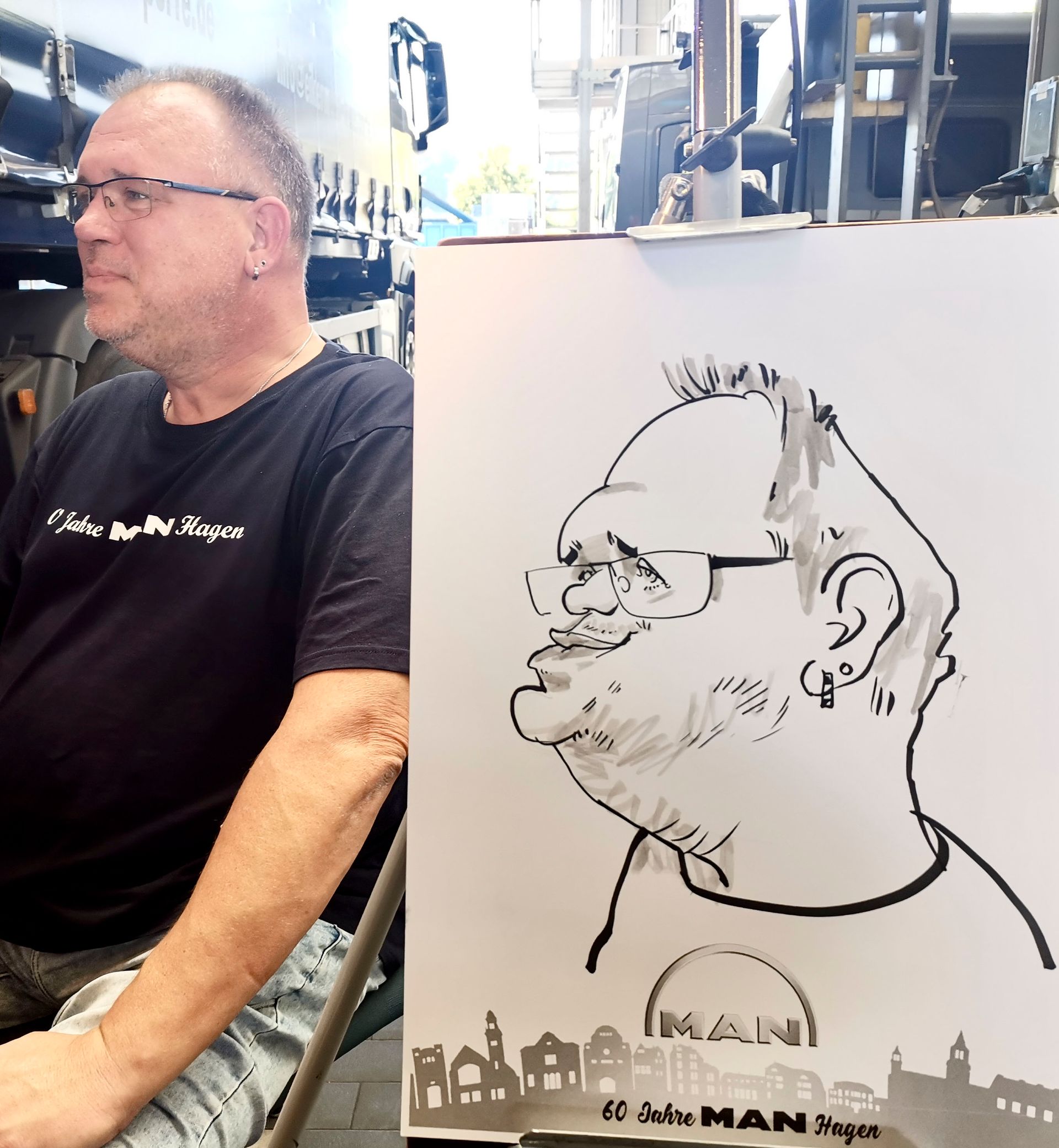 ein Mann sitzt neben einem Gemälde eines Mannes mit Brille