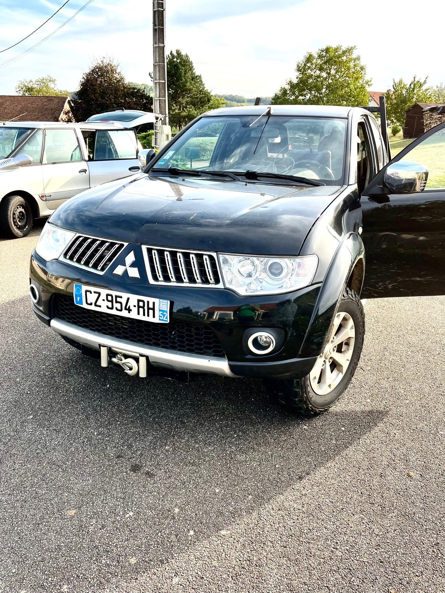 Camionnette Mitsubishi noire stationnée sur l'asphalte. Plaque d'immatriculation : CZ-954-RH.