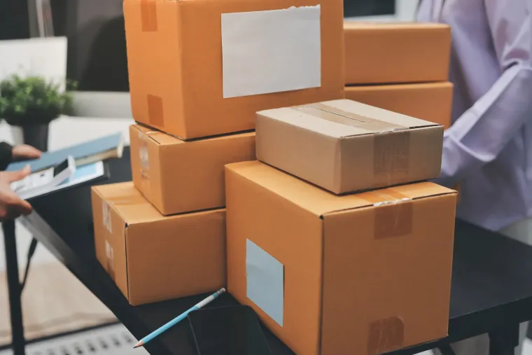 Pila de cajas de cartón sobre una mesa, posiblemente para envío.