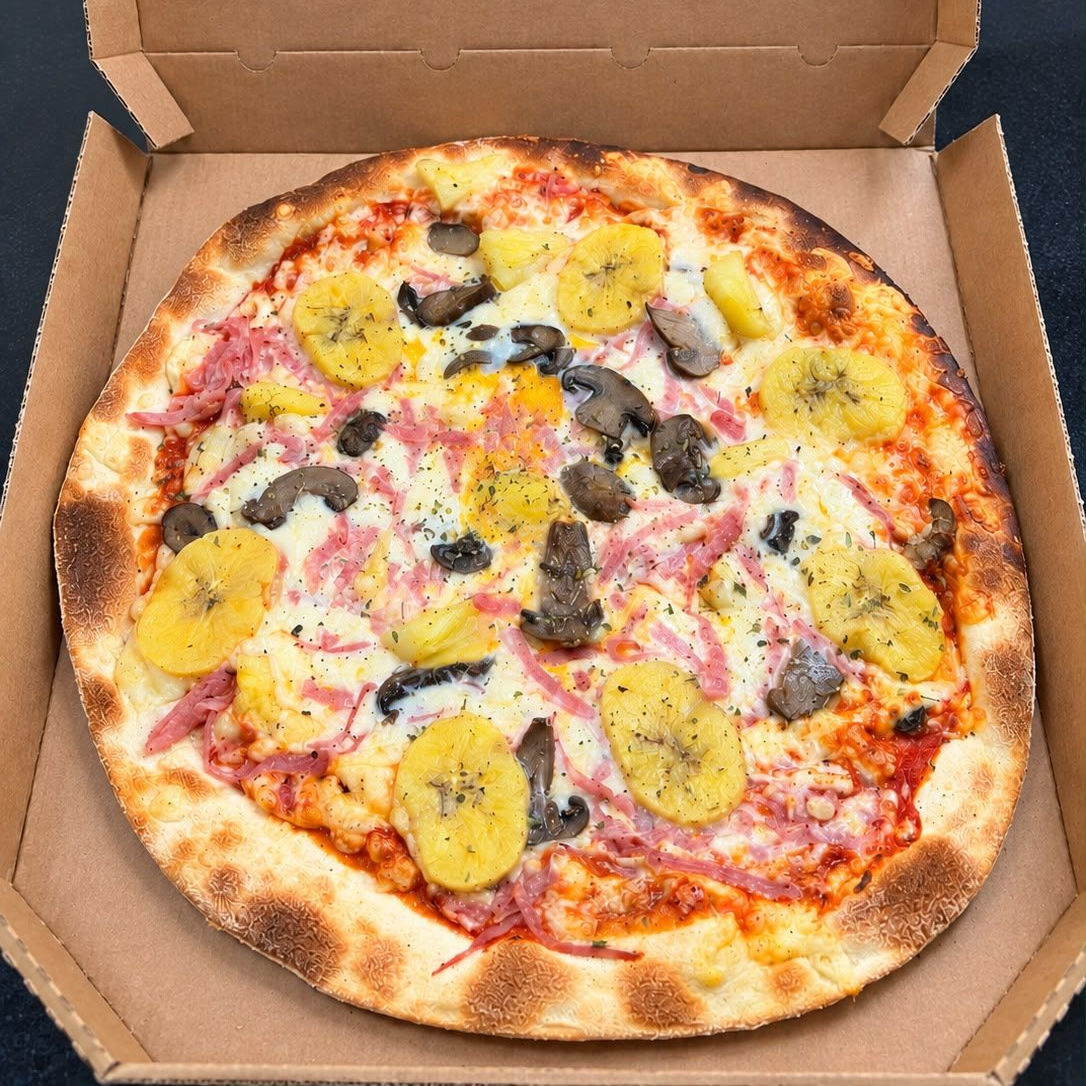 Pizza Margherita con albahaca, tomate y aceitunas negras sobre una mesa de madera