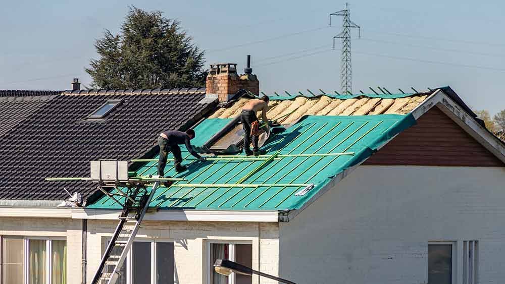 Eine Gruppe Männer arbeitet auf dem Dach eines Hauses.