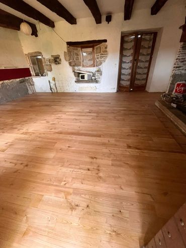 Une personne utilise une perceuse électrique pour fixer des planches de terrasse en bois.