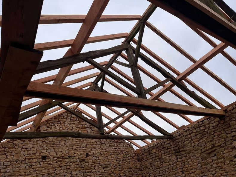 Charpente de toit en bois en construction sur fond de ciel bleu.