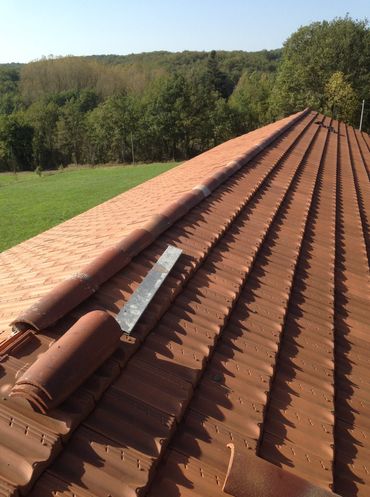 Un ouvrier pose les tuiles sur une maison en construction.