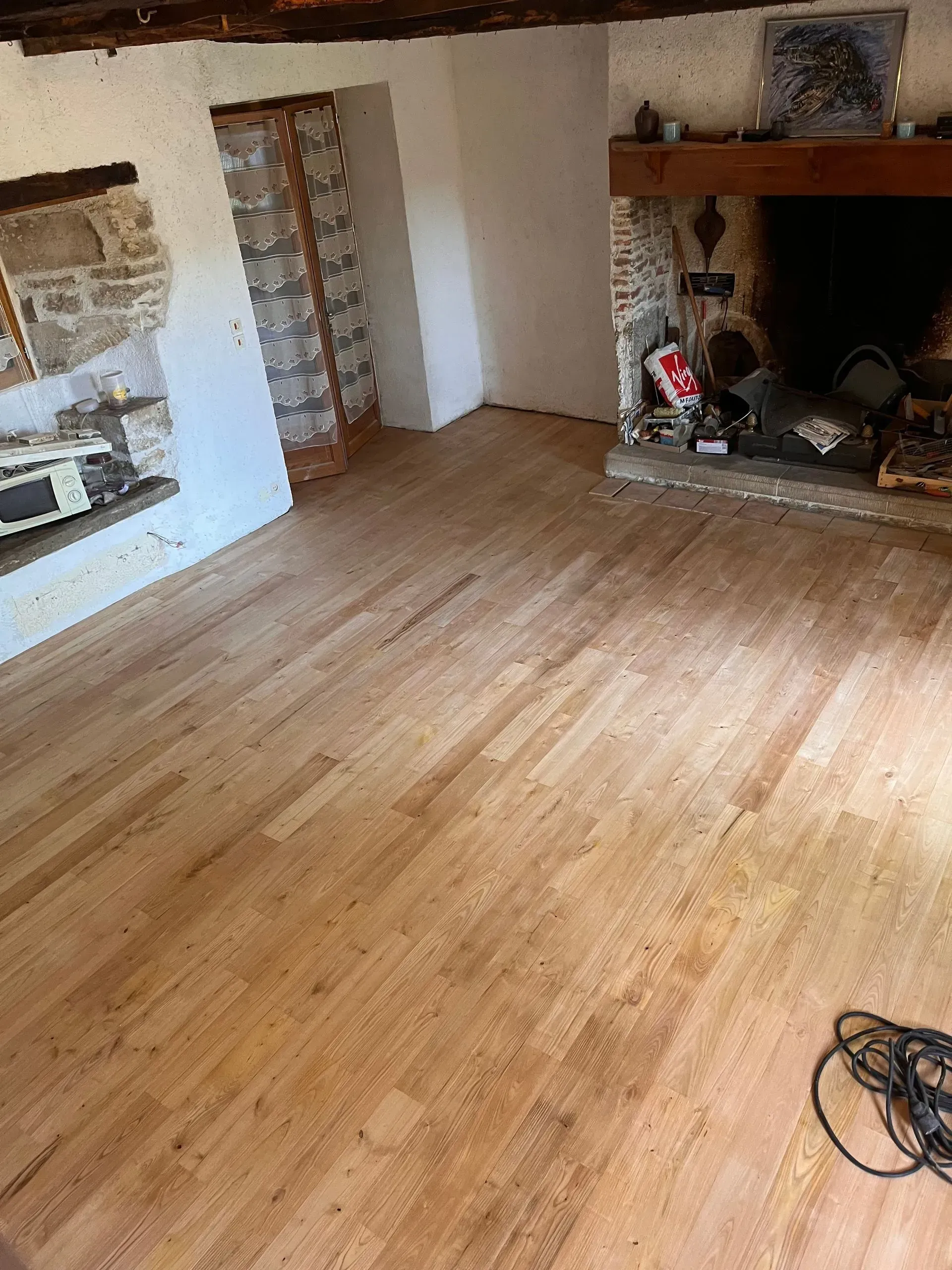 Une personne mesure et marque une planche de bois avec un mètre ruban et une équerre à côté d'une perceuse jaune.