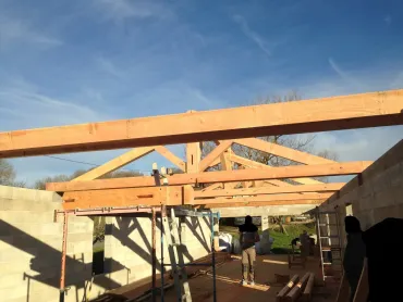 Bâtiment en pierre en rénovation avec une charpente de toit en bois.