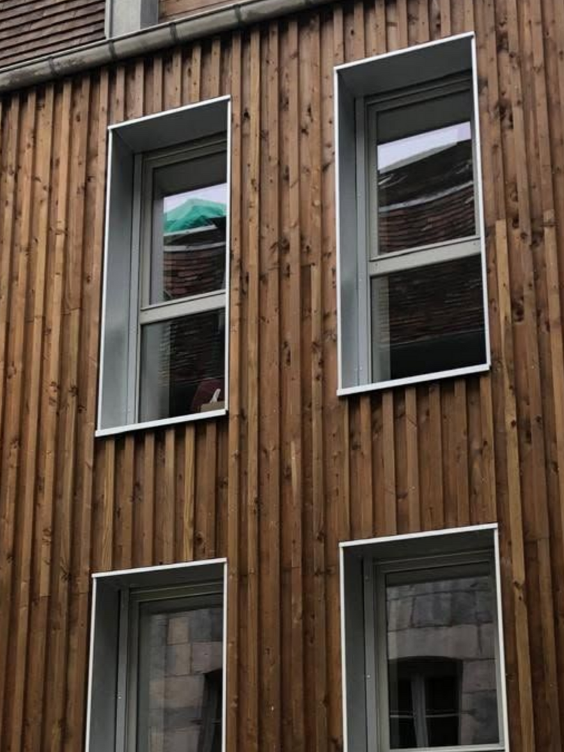 Bâtiment moderne avec bardage bois et fenêtres rectangulaires.