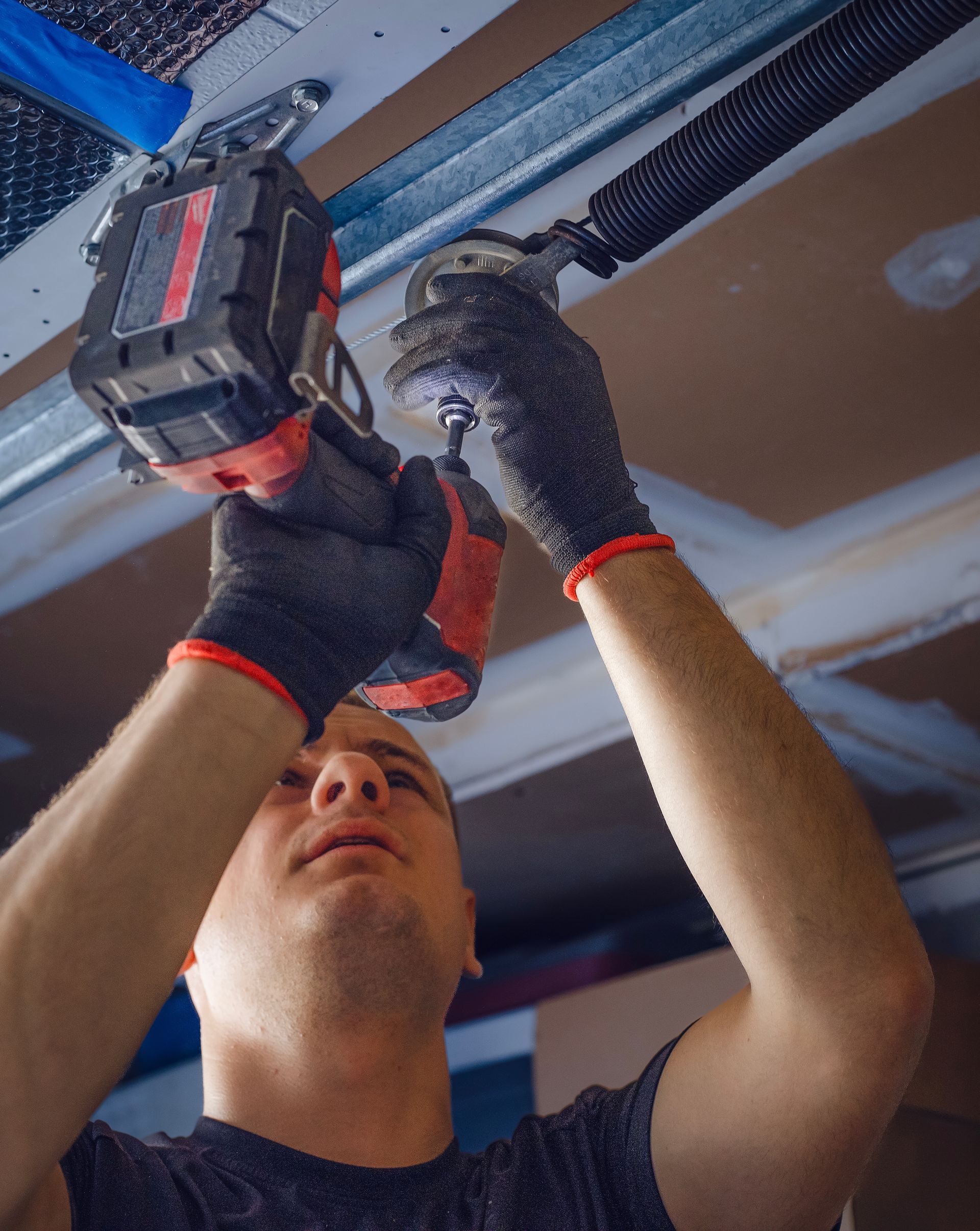 Installation d’un mécanisme de porte de garage avec une perceuse.