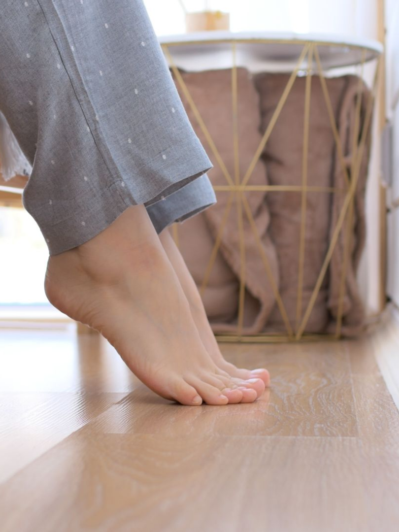 Pieds nus sur un parquet, à côté d'une table d'appoint.