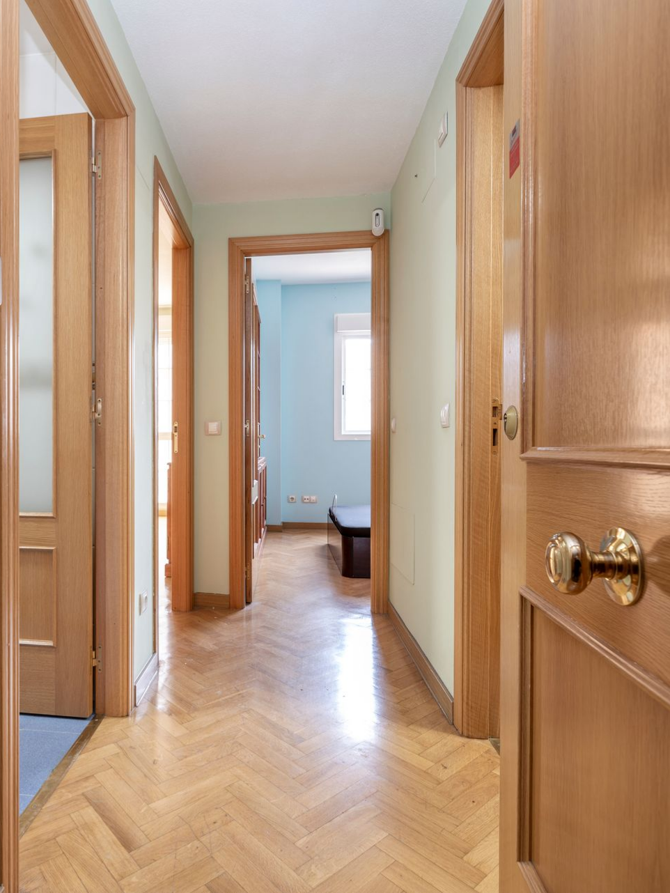 Couloir étroit avec des portes ouvertes et un parquet chevron.