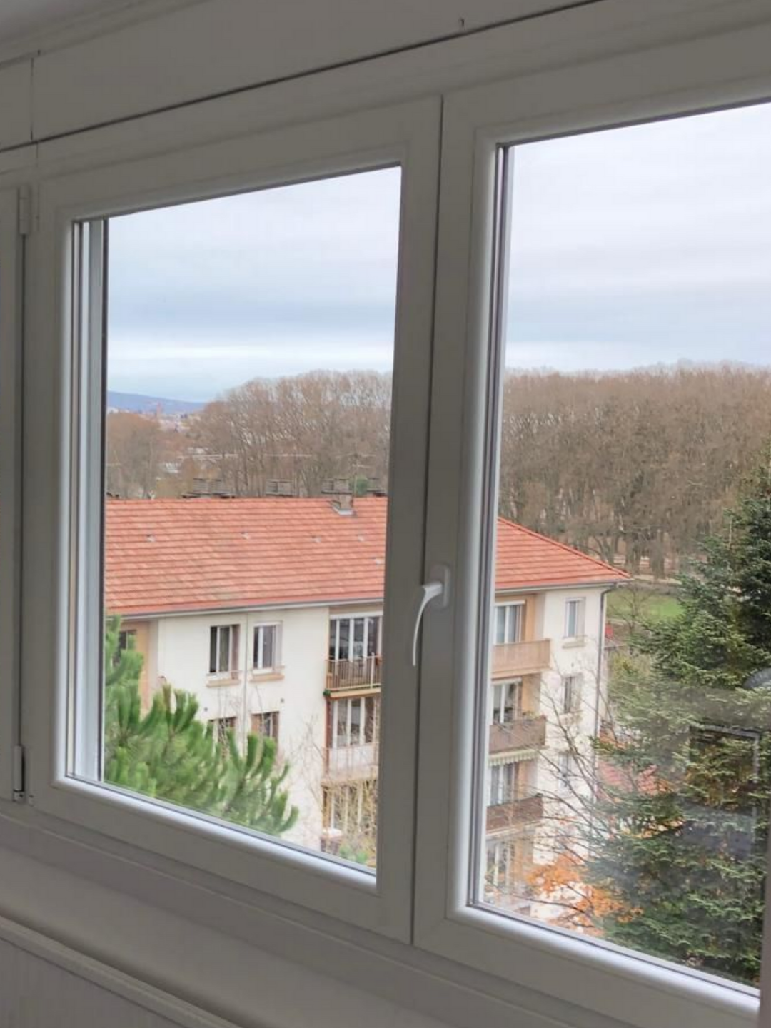Fenêtre blanche en PVC à double vantaux.