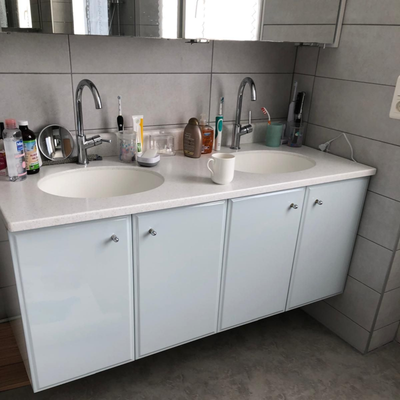 Meuble lavabo avec robinetterie chromée, miroir et murs carrelés.