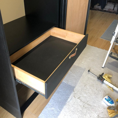 Tiroir ouvert dans un dressing noir et bois.