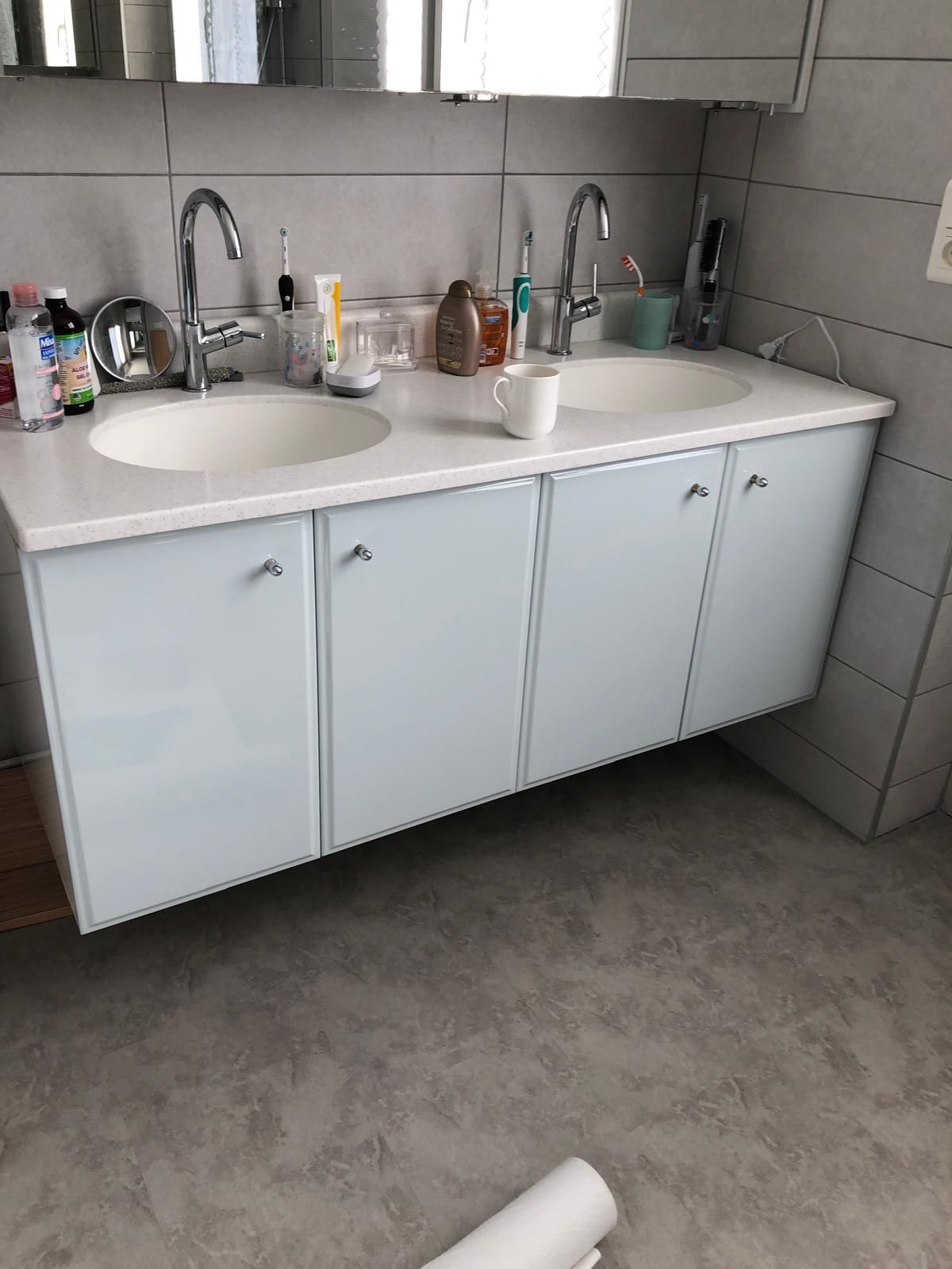Meuble lavabo double vasque, articles de toilette et miroir contre des murs carrelés.