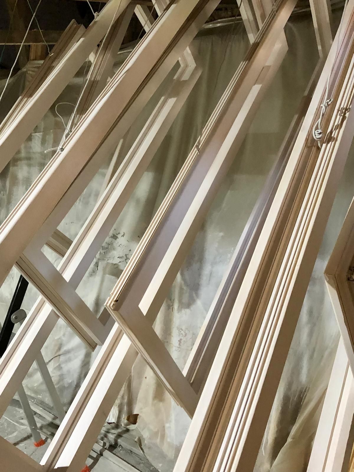 Gros plan sur des cadres ou supports de fenêtres en métal beige empilés, avec des panneaux de verre réfléchissants.