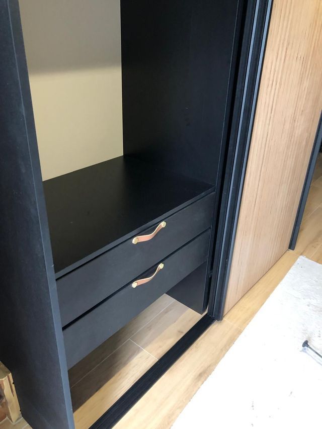 Armoire noire avec deux tiroirs et une porte coulissante en bois sur la droite.